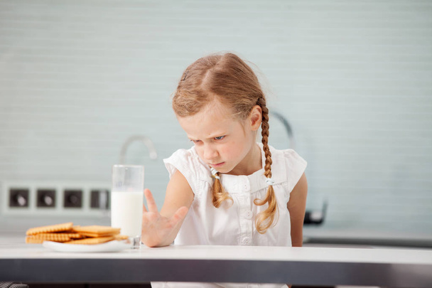 Child looks with disgust for food. Poor Appetite. Little girl does not like milk - Φωτογραφία, εικόνα