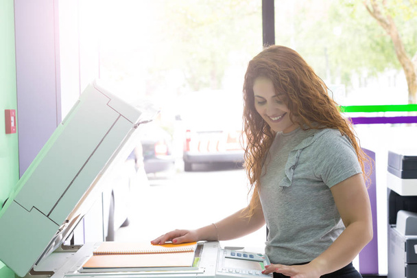 Une jeune étudiante dans un centre de photocopie prenant quelques copies pour ses examens finaux
  - Photo, image