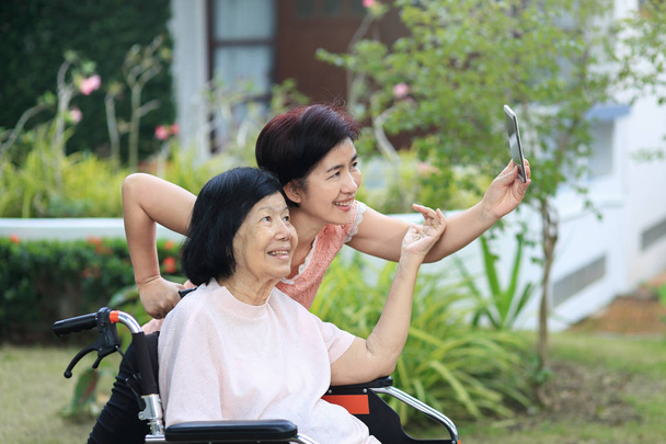 Lánya gondozó az idős ázsiai nő, ezt a selfie, boldog, mosolyog a háztáji. - Fotó, kép