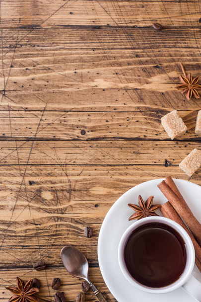 Cup of coffee, brown sugar and cinnamon with anise on a wooden background. Copy space. - Photo, image