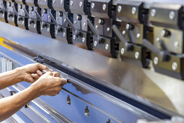 The technician operator use hydraulic bending machine. The sheet metal manufacturing process. - Φωτογραφία, εικόνα