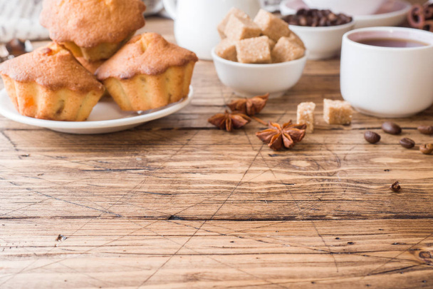 Breakfast coffee with milk, pastries, brown sugar and cinnamon with anise on wooden background - Photo, image