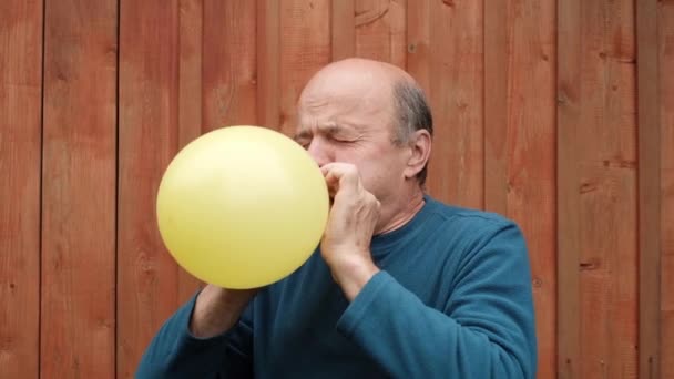 zralý muž foukání balón - Záběry, video