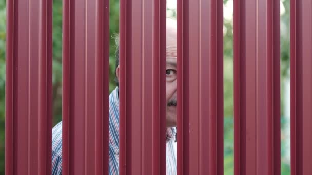 Senior homme regardant à travers la clôture espionnage sur son voisin
 - Séquence, vidéo