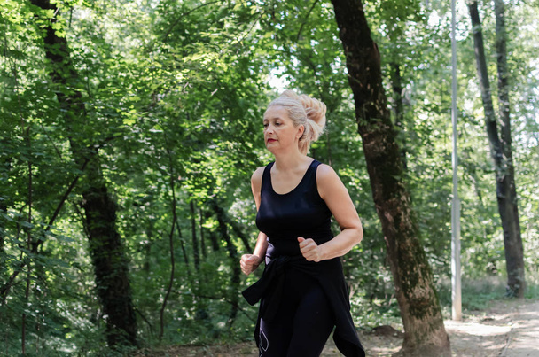 Portrait of senior woman running in the park. Mature woman keeping fit and healthy. - Photo, Image