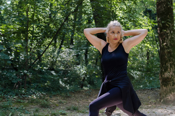 Portrait of senior woman stretching out in nature. - Photo, image