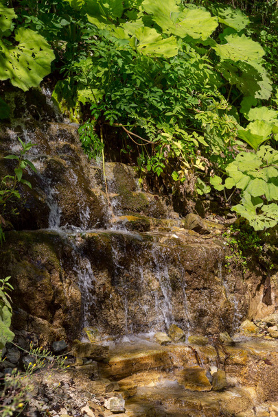 ein kleiner wasserfall, der an einem sonnigen sommertag vom berg fließt (region tzoumerka, griechenland, mountain pindos). - Foto, Bild