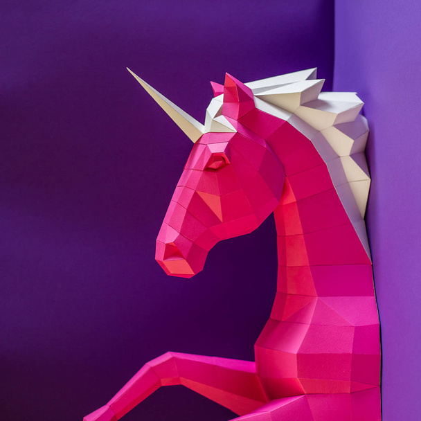 Head of a unicorn of paper on a pink and blue background. - Фото, изображение