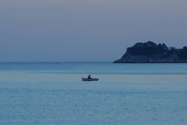 Fisherman boat is fishing on the sea near the coast on summer evening. Scala Potamia Greece Thassos - Photo, Image
