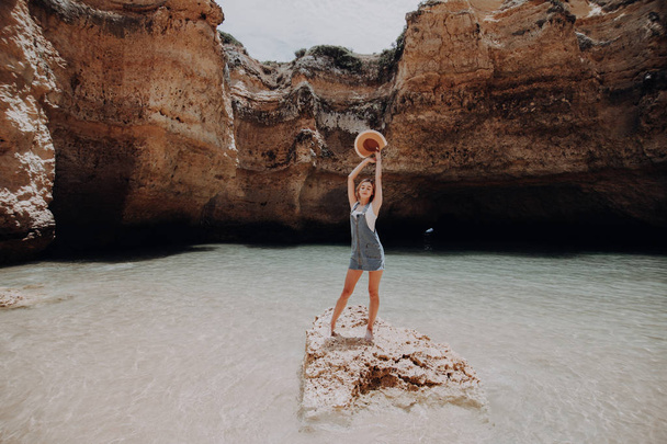 Mujer joven de pie hermosa naturaleza en la playa de roca con los brazos levantados disfrutar de su vocación de verano
 - Foto, Imagen