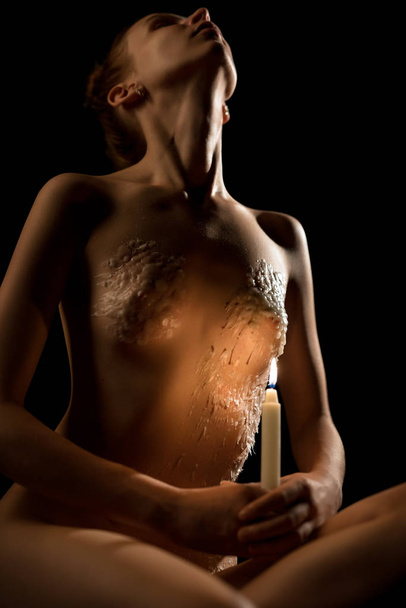 Woman in the nude with burning candle in the dark - Foto, immagini