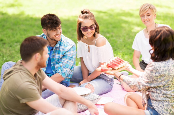 happy friends eating watermelon at summer picnic - Foto, Imagen