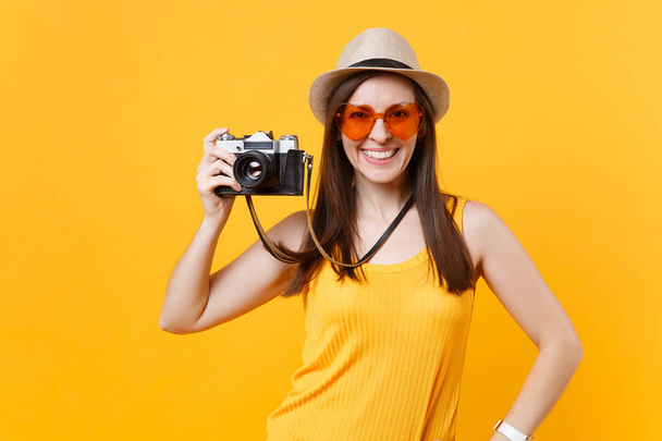 Donna turistica in estate abiti casual, cappello scattare foto su retro fotocamera vintage isolato su sfondo giallo. Ragazza che viaggia all'estero per viaggiare durante il fine settimana fuga. Concetto di volo aereo
 - Foto, immagini