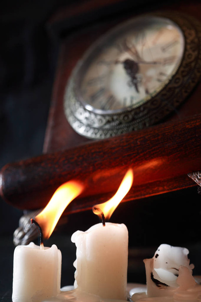 Vintage still life with lighting candles near old clock - Photo, Image