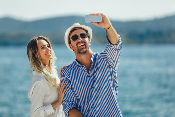 Para zakochanych, ciesząc się latem przez morze zrobić zdjęcie selfie z inteligentny telefon - Zdjęcie, obraz
