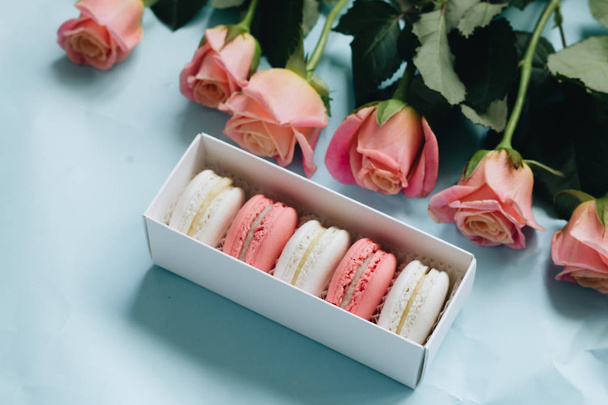 composition of delicious macaroons and pink roses on blue table - Φωτογραφία, εικόνα