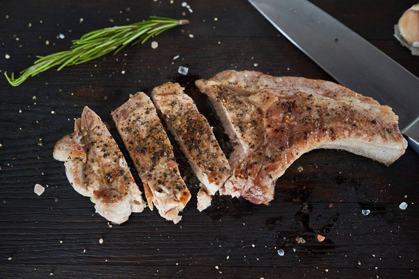 Cutted grilled pork loin steaks on black table - Photo, Image