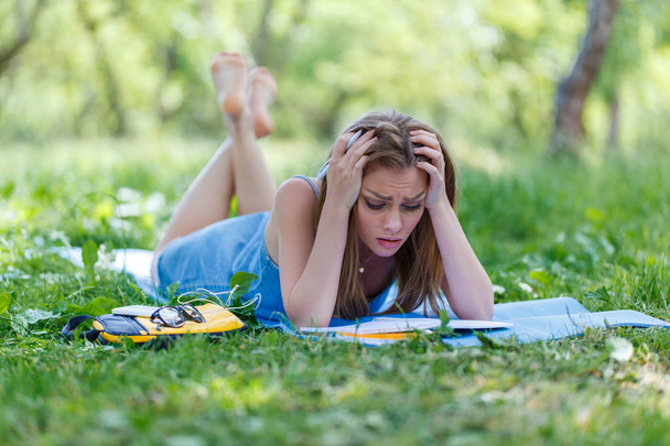 Beautiful young woman writing in her notebook, in the park - Fotoğraf, Görsel