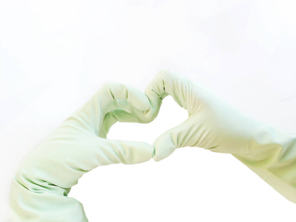 Handen in een economische handschoen van rode kleur voor huishoudelijke chemie zijn geïsoleerd op een gekleurde achtergrond voor een design - Foto, afbeelding
