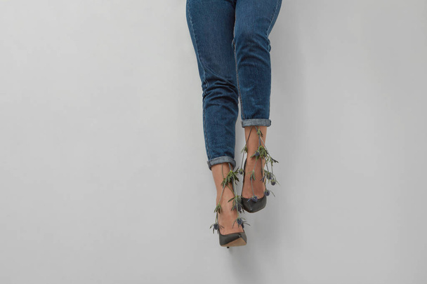 Slender legs of a woman in jeans with flowers on a gray background. Place for text. - Φωτογραφία, εικόνα