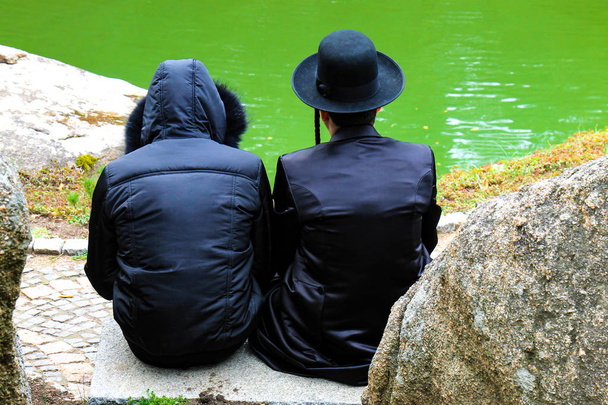 2 hasidic άνδρες, εβραϊκή οικογένεια, με παραδοσιακά ρούχα διαβάσει μια προσευχή στο πάρκο Uman, την Ουκρανία, τη στιγμή της το εβραϊκό νέο Ναι, Rosh-ha-Shana - Φωτογραφία, εικόνα