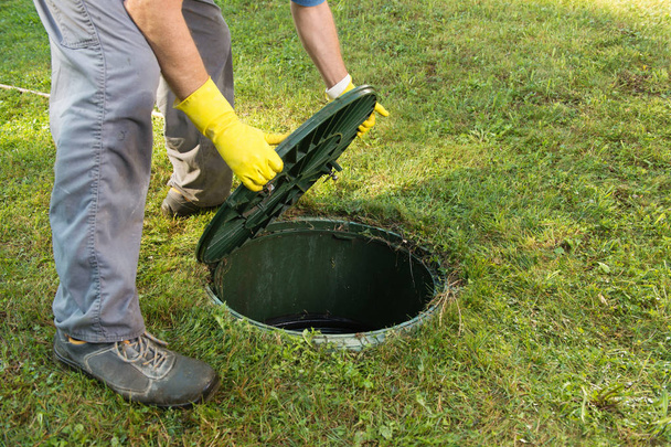 Opening septic tank lid. Cleaning and unblocking septic system and draining pipes - Photo, Image