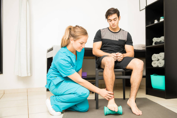 若い理学療法士病院で運動選手の足底筋膜炎の治療の完全な長さ - 写真・画像