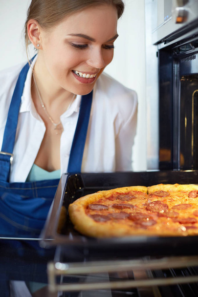 Happy young woman cooking pizza at home - Zdjęcie, obraz