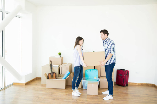 Seitenansicht eines Mannes und einer Frau, die schwere Pappkartons heben, während sie ein neues Zuhause einrichten - Foto, Bild
