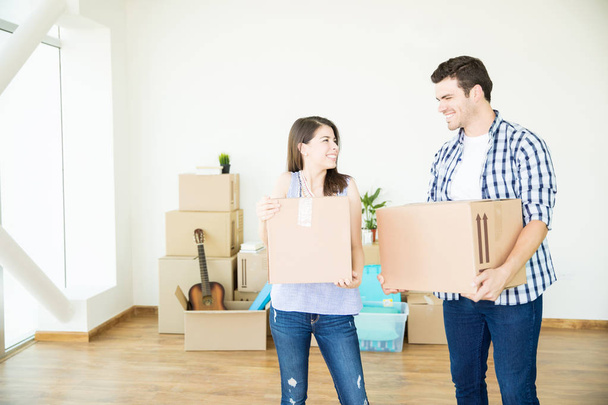 Casal sorrindo enquanto se move caixas onduladas em nova casa
 - Foto, Imagem