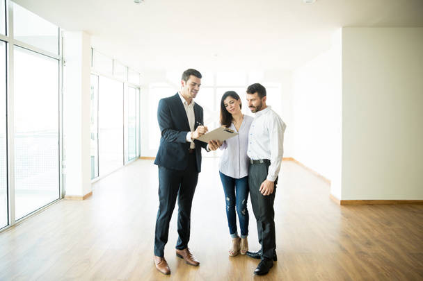 Mediados de adulto agente inmobiliario explicando el acuerdo de pareja en nuevo apartamento
 - Foto, Imagen