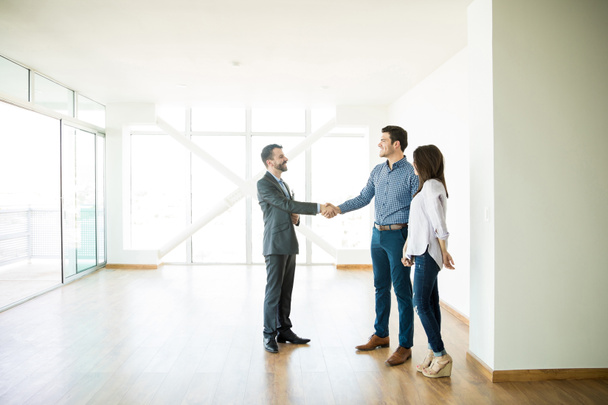 Mid adult estate agent greeting couple during visit to new home - Photo, image