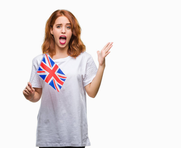 受賞式祝う勝利笑顔で叫び、手を上げた非常に幸せと興奮、孤立した背景の上イギリスの旗を保持している若い美しい女性 - 写真・画像