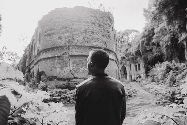 tourist man near the ruins of an old military fort with beautiful architecture large arch walls and columns - Фото, изображение