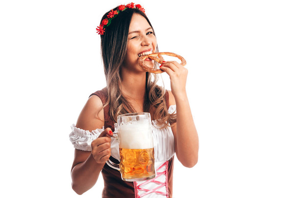 ελκυστική κοπέλα με παραδοσιακή ενδυμασία γερμανική κουλουράκι και μπύρα στο Oktoberfest, απομονώνονται σε λευκό - Φωτογραφία, εικόνα