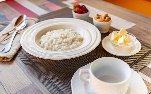 Gezond ontbijt. Rijst pap kom met bessen en noten op de tafel, warm en gezond ontbijt eten, zijaanzicht - Foto, afbeelding