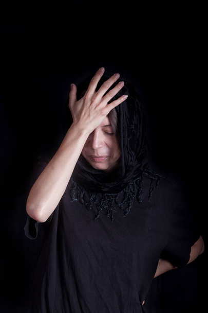 Žena na černém pozadí s rukou na hlavu v gestu nouzi - Fotografie, Obrázek