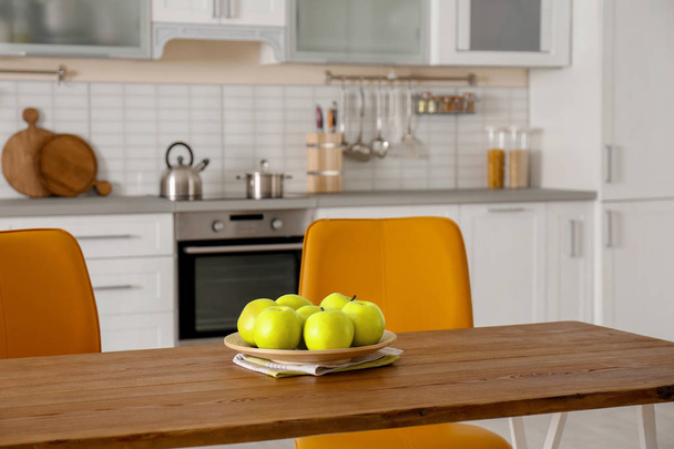 Table with ripe apples in stylish kitchen interior - Foto, afbeelding