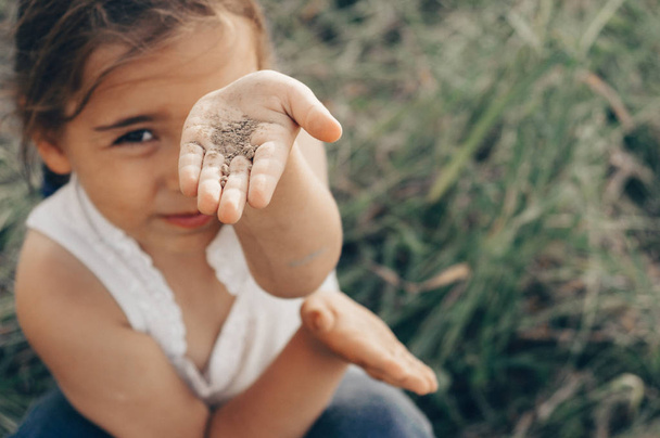 Petite fille jouant dans un champ de maïs à l'automne. Un enfant tenant une épi de maïs. Récolte avec les enfants. Activités d'automne pour les enfants
 - Photo, image