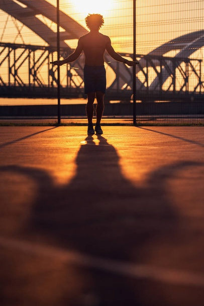 Sportos fiatalember jumping kötelet kívül napsütéses reggel. - Fotó, kép