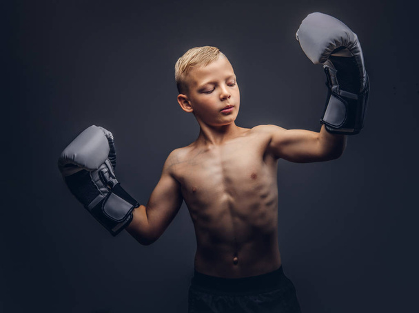Młody chłopak przystojny bokser z rękawice bokserskie pozowanie w studio. - Zdjęcie, obraz