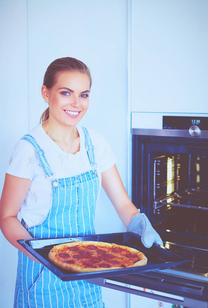 Happy young woman cooking pizza at home - Fotoğraf, Görsel