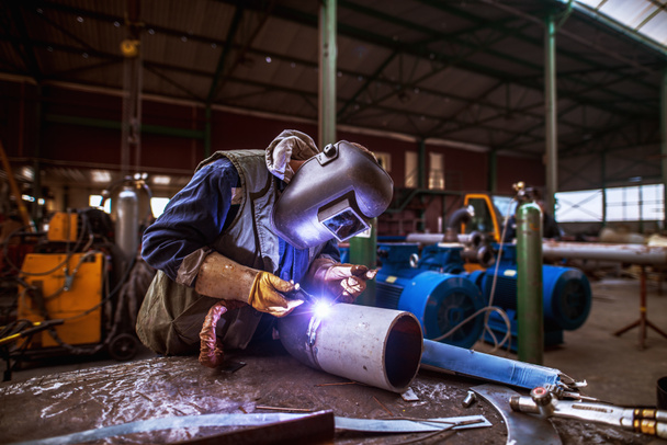 Промисловий працівник чоловічої статі в захисному рівномірному ремонті металевих труб
. - Фото, зображення