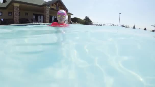 Pieni tyttö hauskaa uinti ulkouima-altaassa kesällä - Materiaali, video