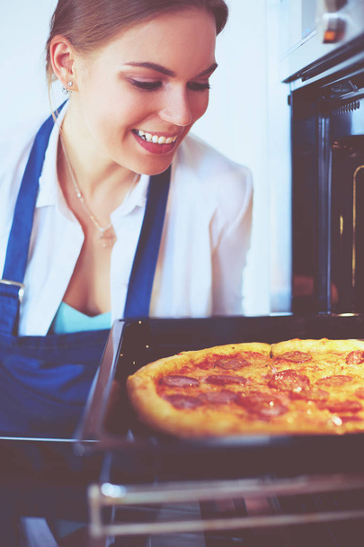 Happy young woman cooking pizza at home - Fotó, kép