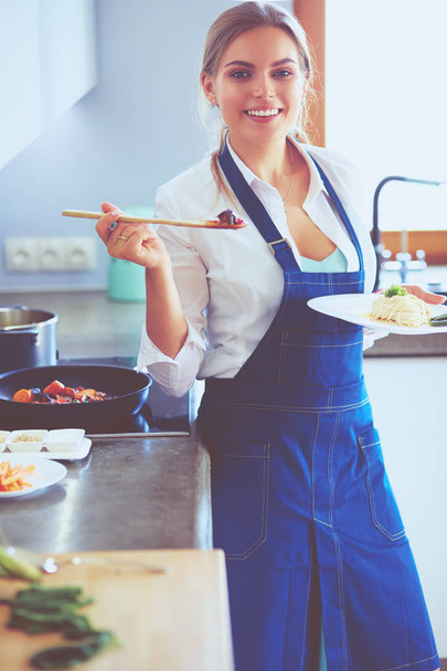 Young woman standing by the stove in the kitchen - Photo, image