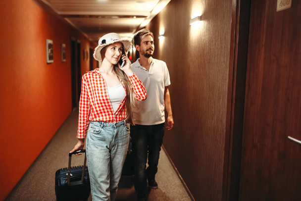 Uśmiechający się para z walizkami w korytarzu. Podróżowanie i turystyka pojęcie. Podróżujący z torby w korytarzu - Zdjęcie, obraz