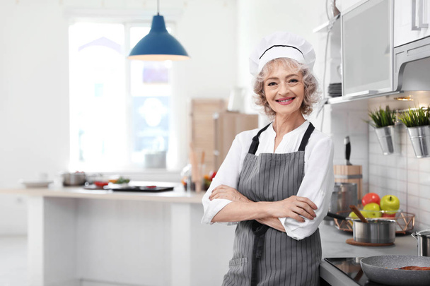 Chef profesional femenino de pie cerca de la mesa en la cocina
 - Foto, imagen