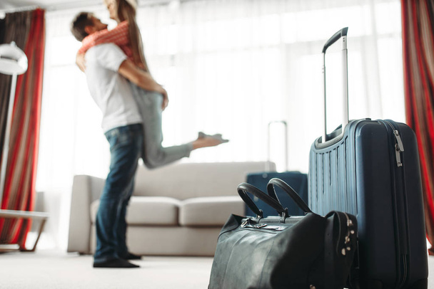 Suitcases prepared for vacation, happy couple hugs on background. Fees on journey concept. Luggage preparation. Travelling or tourism - Photo, Image