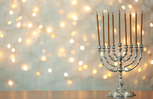 Hanukkah menorah with candles on table against blurred lights - Photo, Image